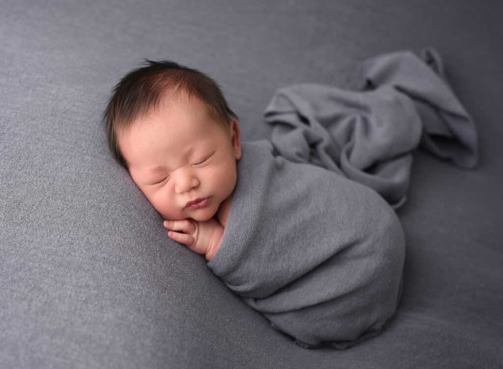 Newborn baby boy Noah wrapped in grey during studio newborn session in Wallingford, Connecticut