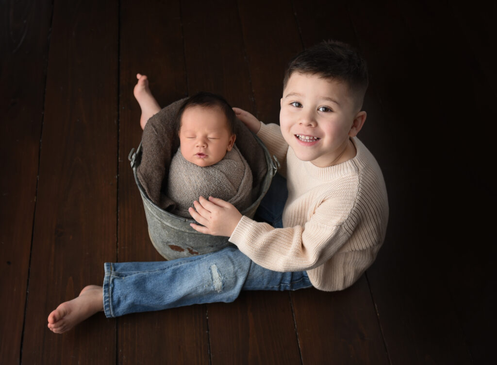 Big brother Ryan holding newborn baby Noah during sibling photo session in Wallingford CT
