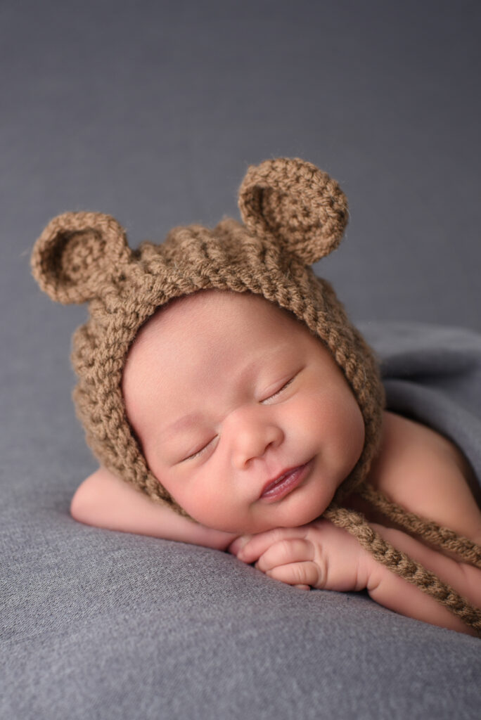 Newborn baby boy Noah in brown teddy bear hat during studio newborn session in Wallingford, Connecticut